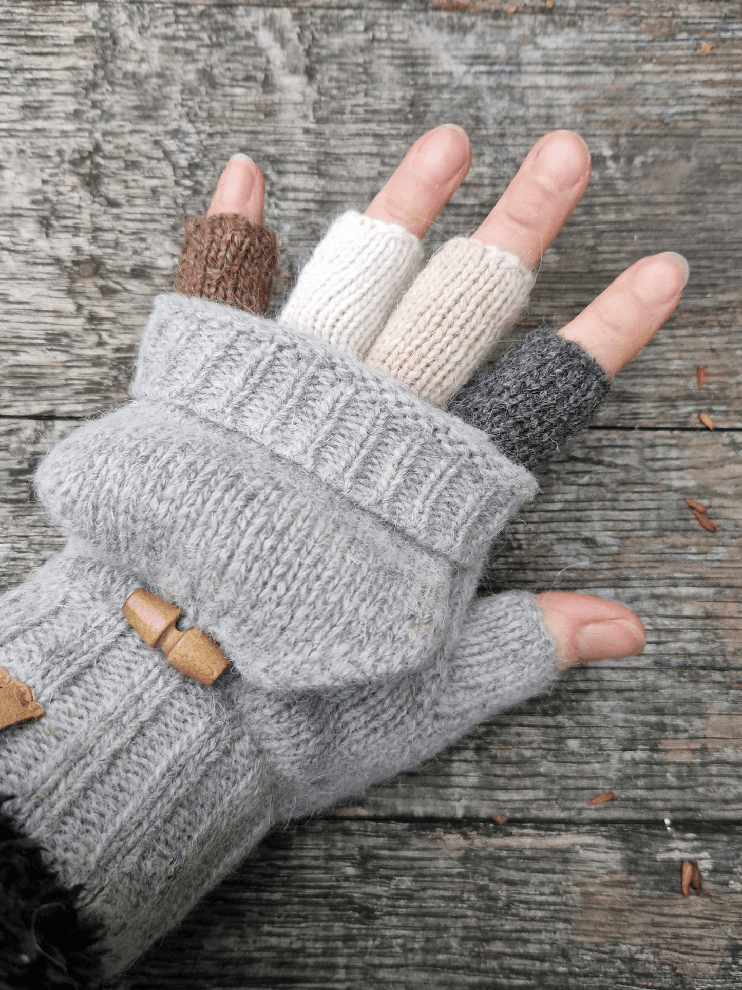 hand wearing knitted fingerless mittens, with different coloured half fingers