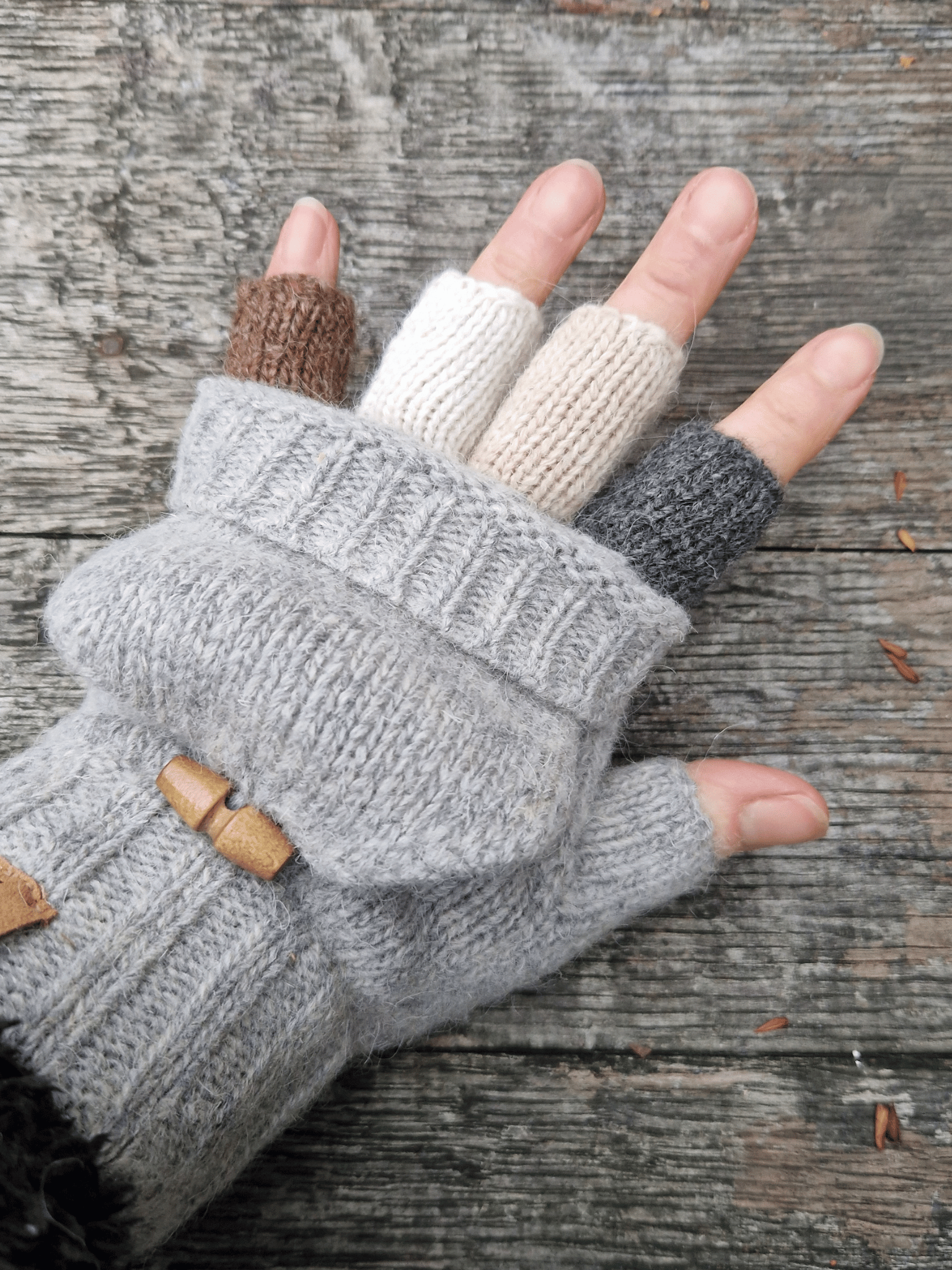 hand wearing knitted fingerless mittens, with different coloured half fingers
