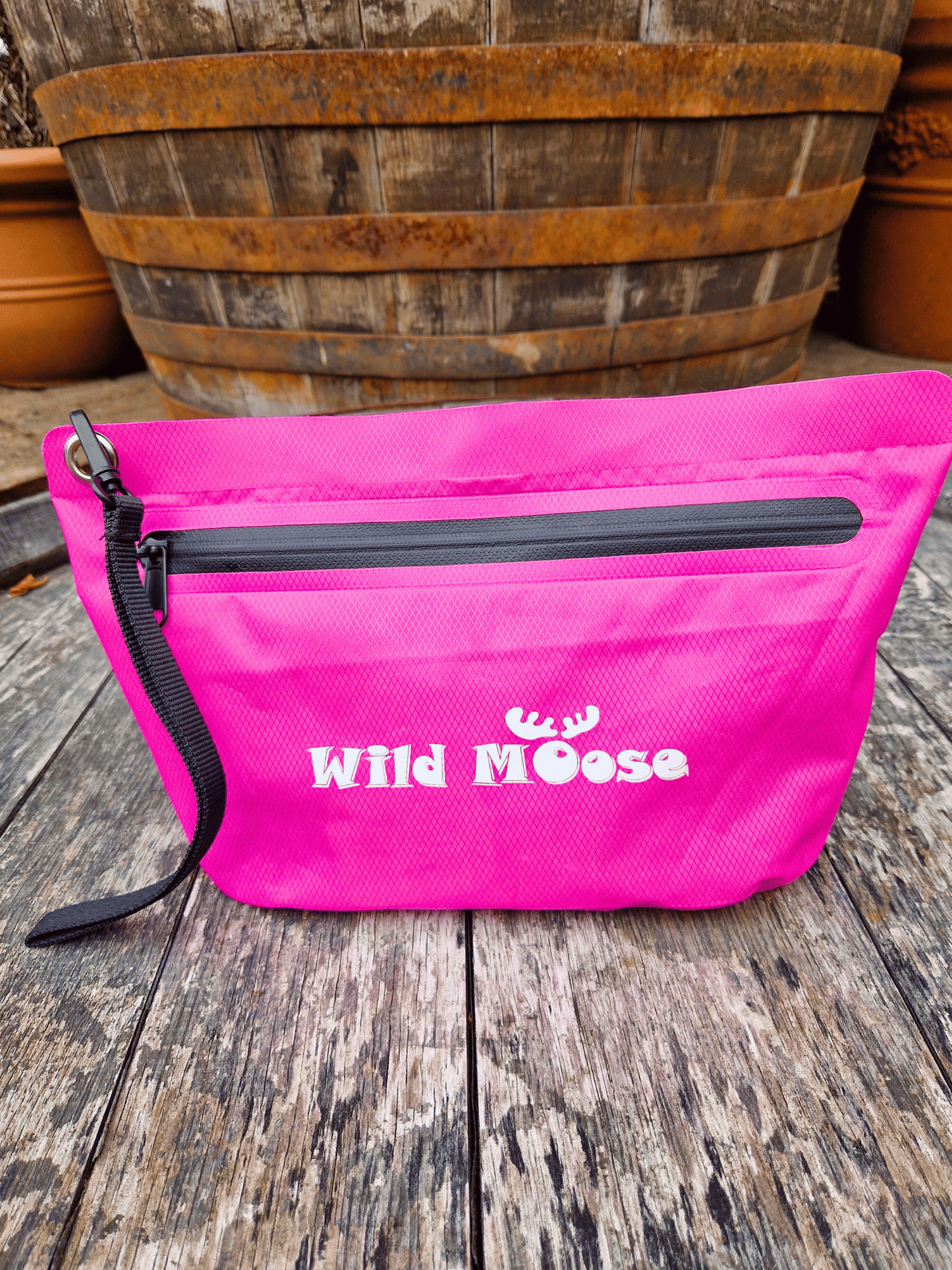 Pink zip up waterproof pouch with 'Wild Moose' branding on a wooden surface