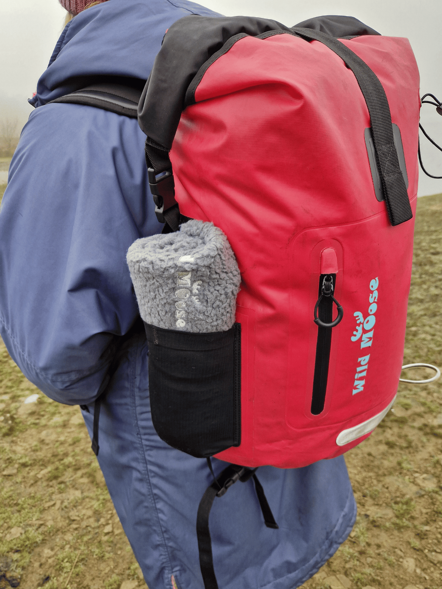 a rolled up changing mat in the stretchy side pocket of the pink Caribou backpack - fleece side showing