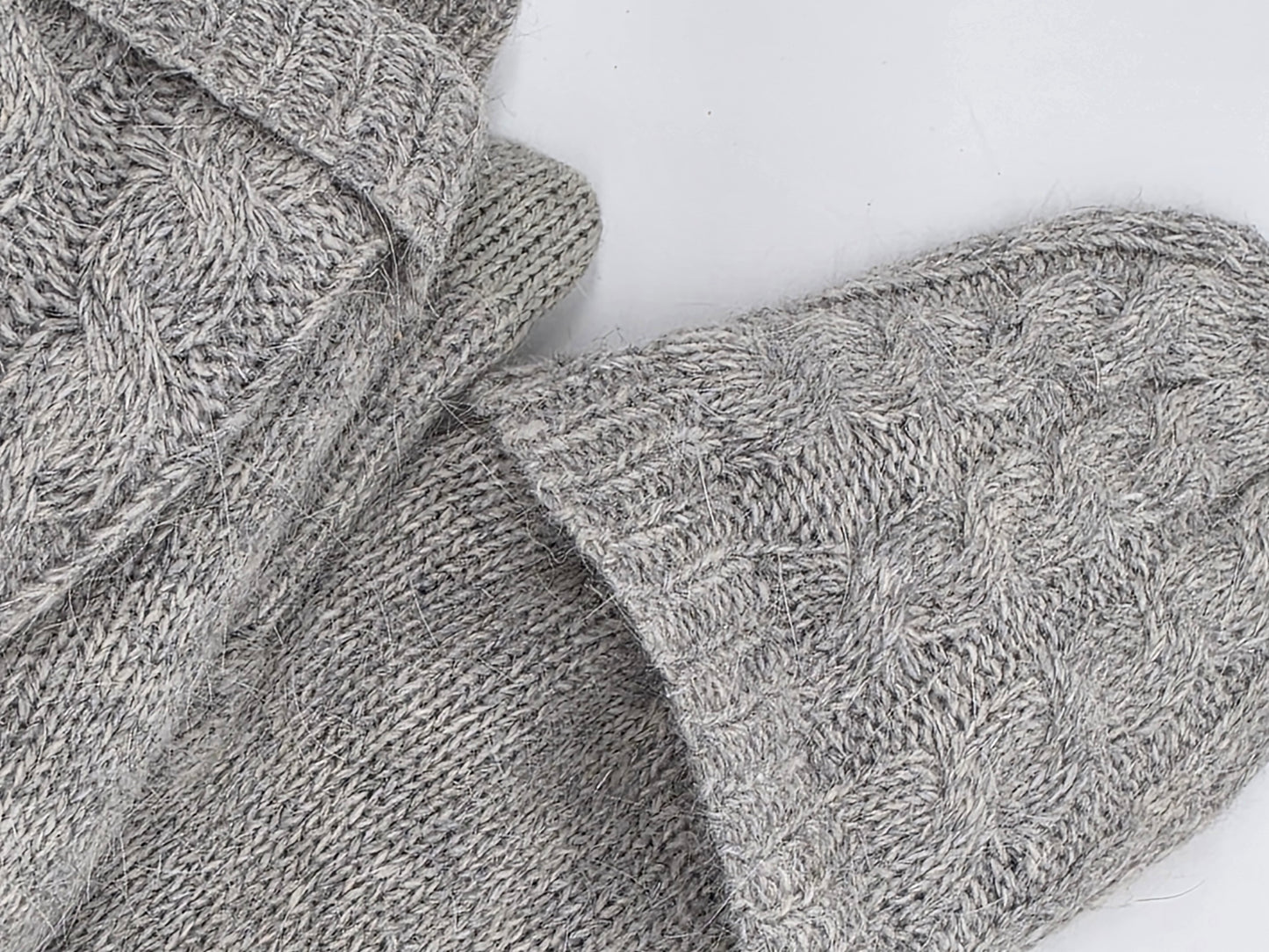 folded over top of grey mittens on a white backdrop.