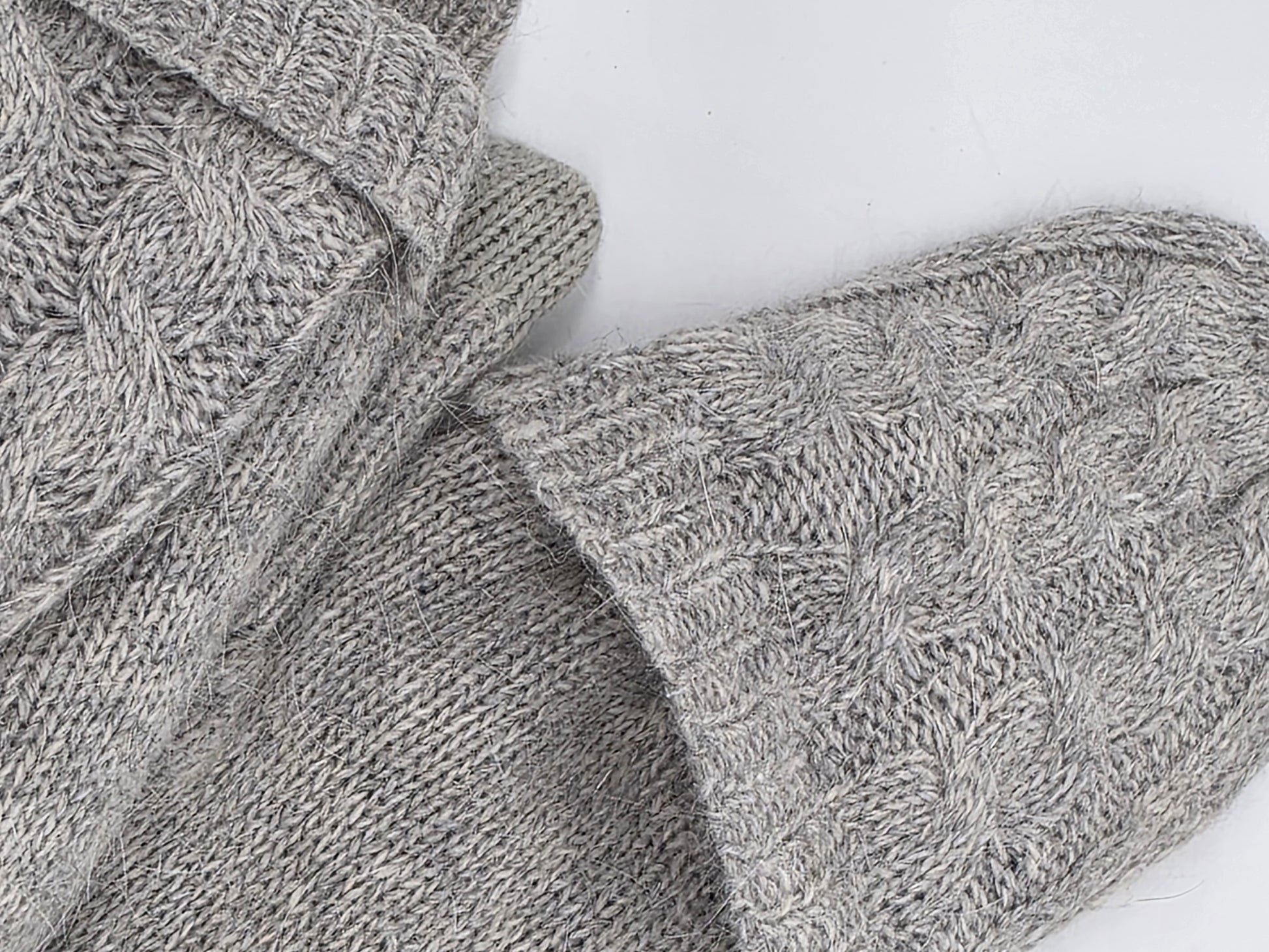 folded over top of grey mittens on a white backdrop.