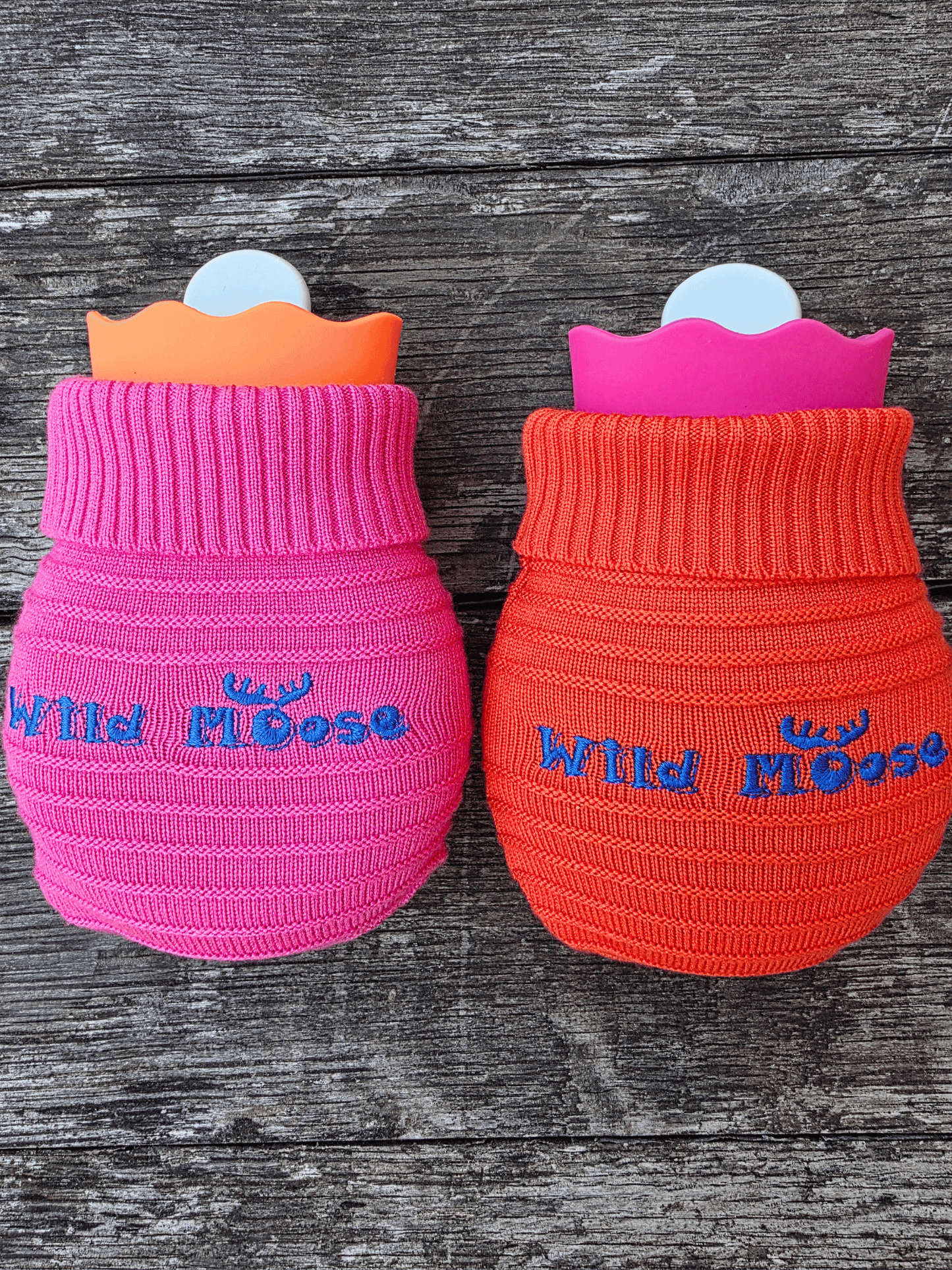 2 mini hot water bottles in a contrasting knitted cover - one bright pink the other bright orange