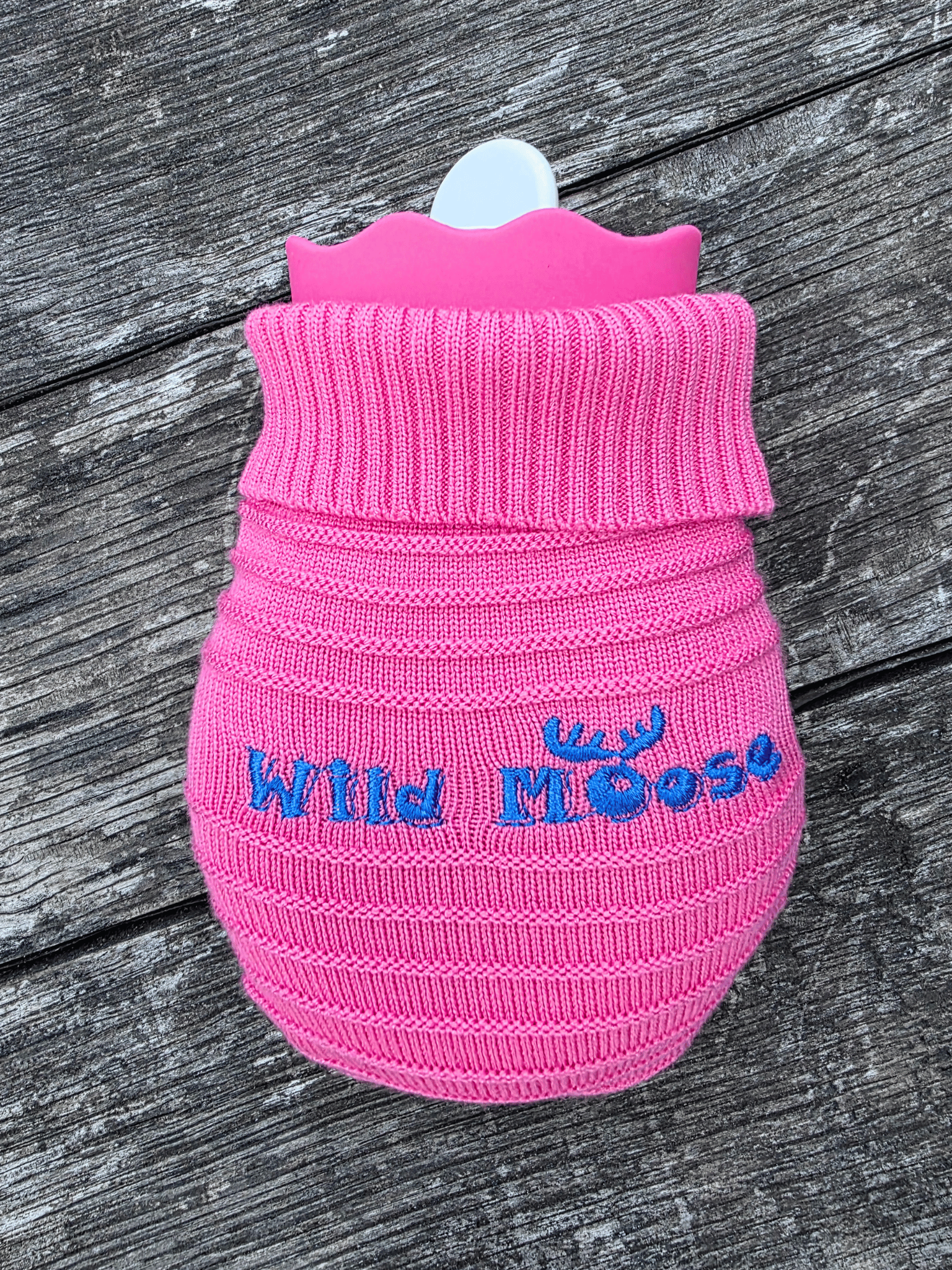 mini hot water bottle in a knitted cover in bright pink