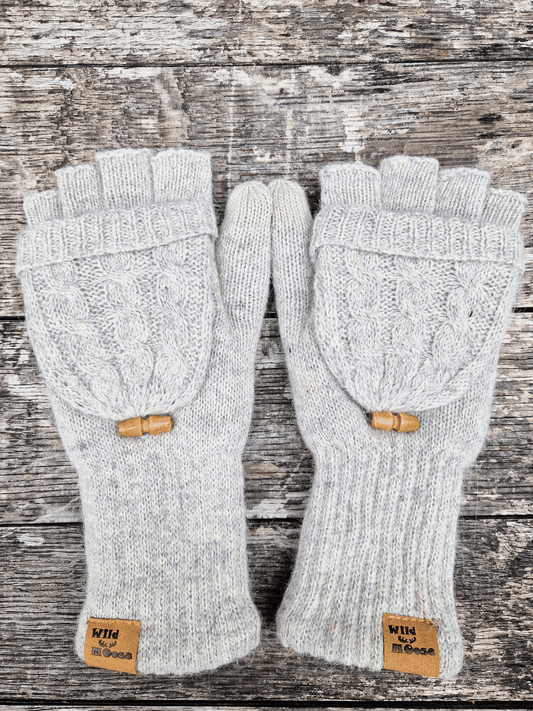 Pair of grey fingerless gloves with wooden buttons on a wooden surface. There is a folded back mitten cover.