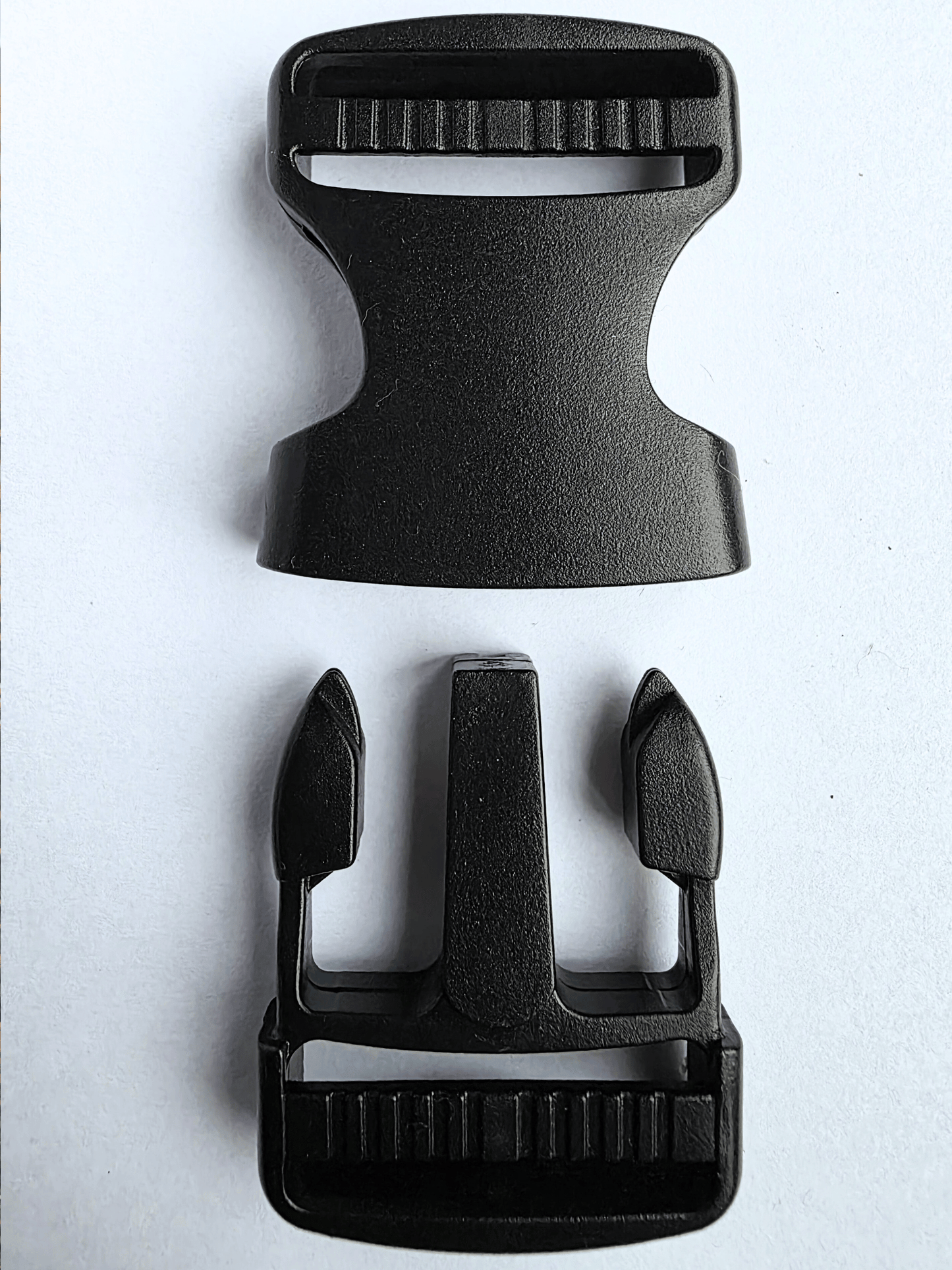 Black, plastic side release buckle shown in 2 separated parts