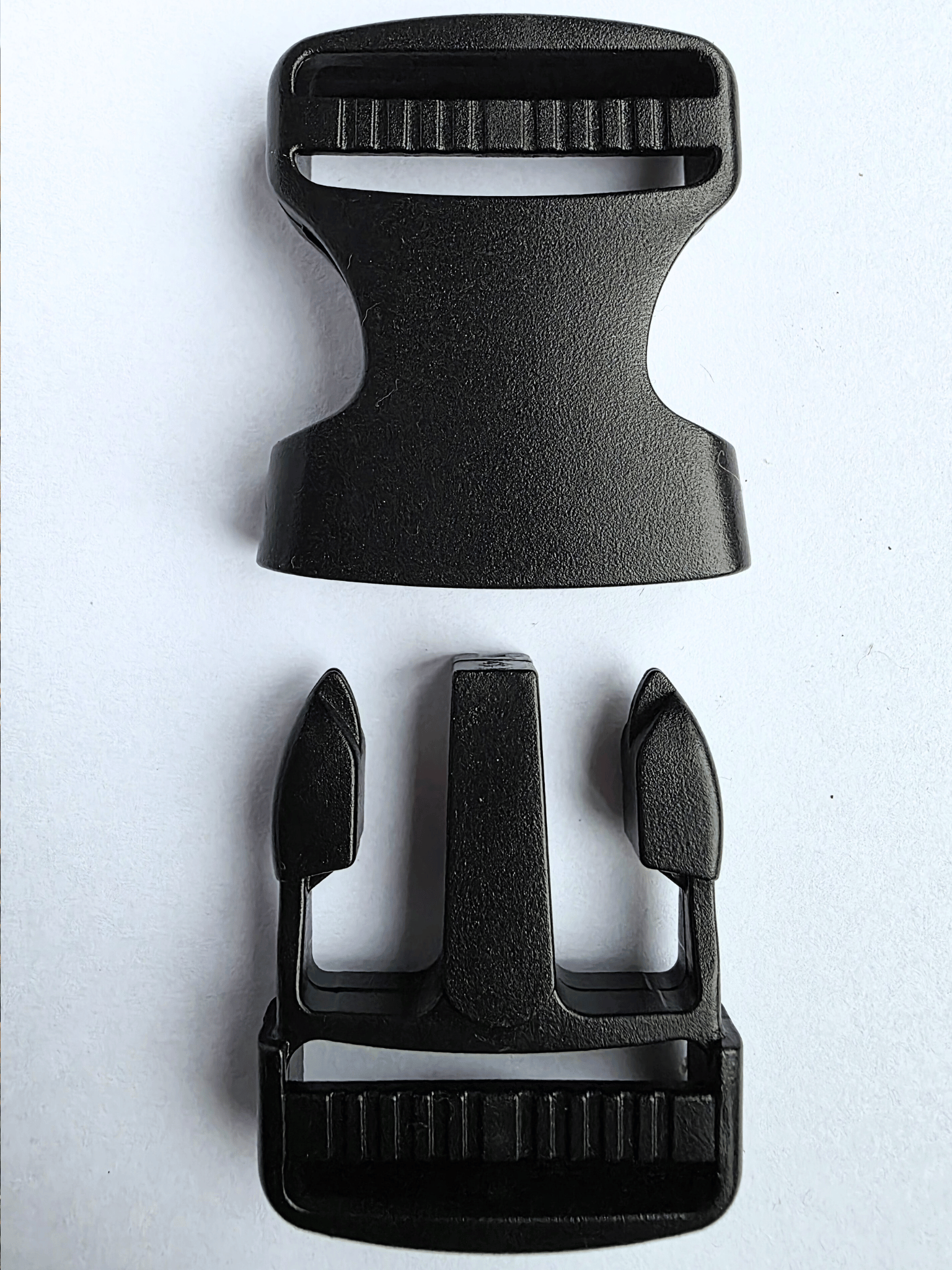 Black, plastic side release buckle shown in 2 separated parts