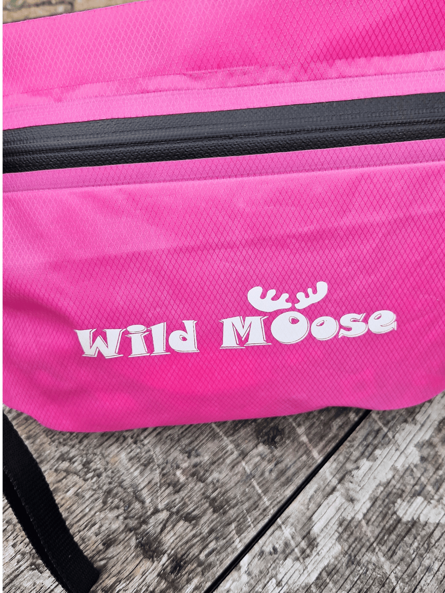 Pink bag with 'Wild Moose' logo on a wooden surface