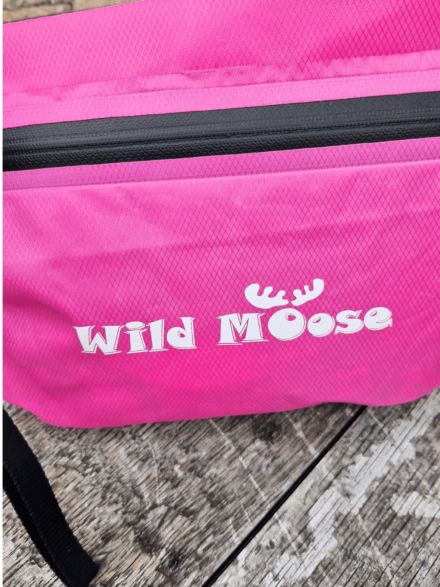 Pink bag with 'Wild Moose' logo on a wooden surface