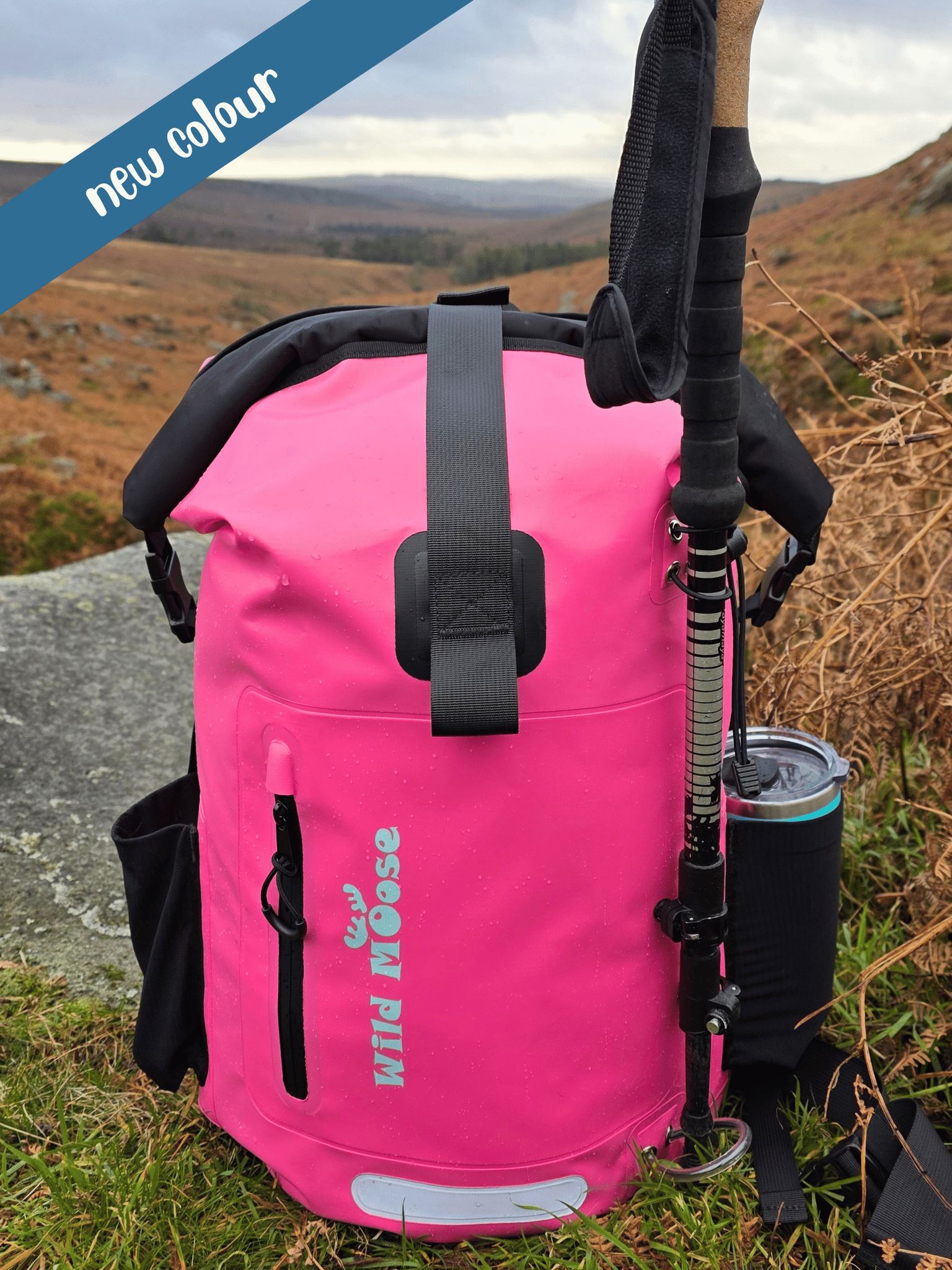 Pink backpack with hiking poles and a cup on a natural background