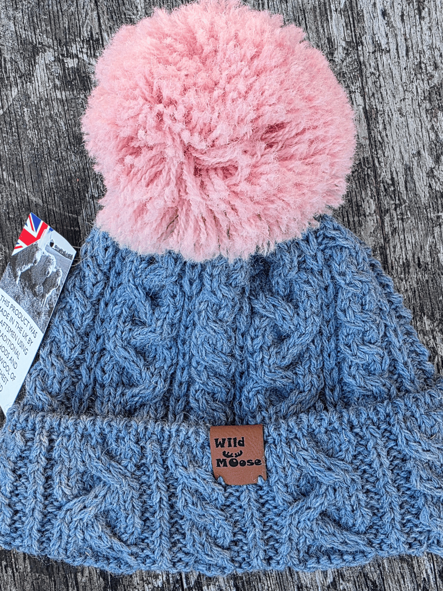 an icy blue cable knit bobble hat with pale pink pom