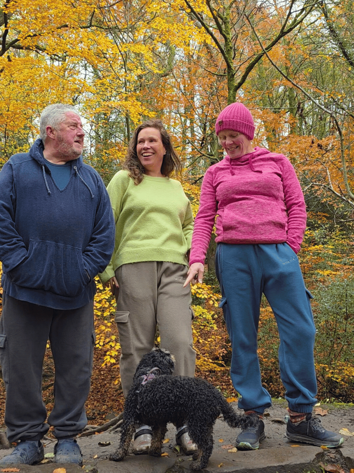 Three people wearing fleece jogging pants, standing in a forest with autumn foliage