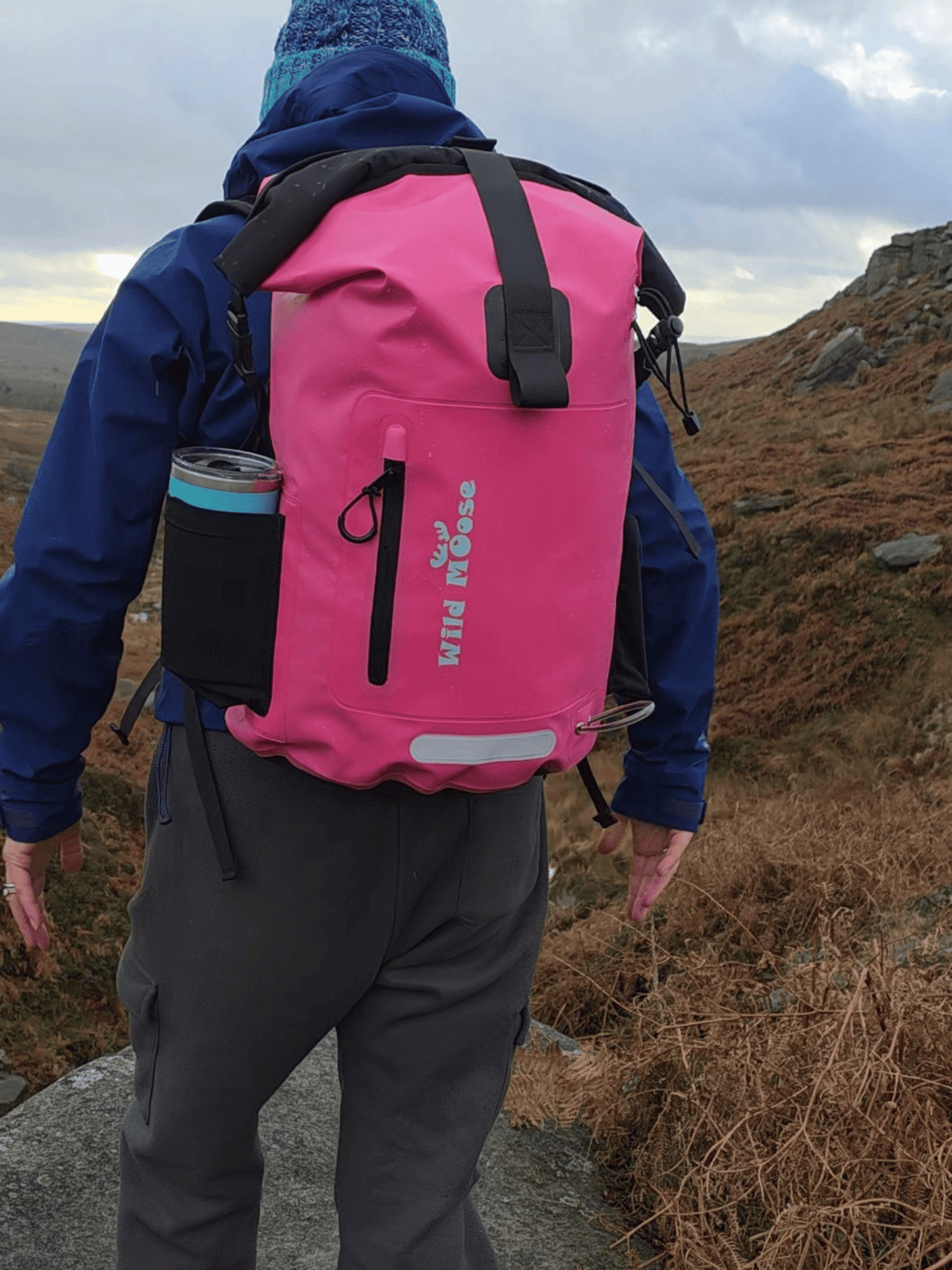 Person wearing a pink backpack with a blue jacket in a mountainous area
