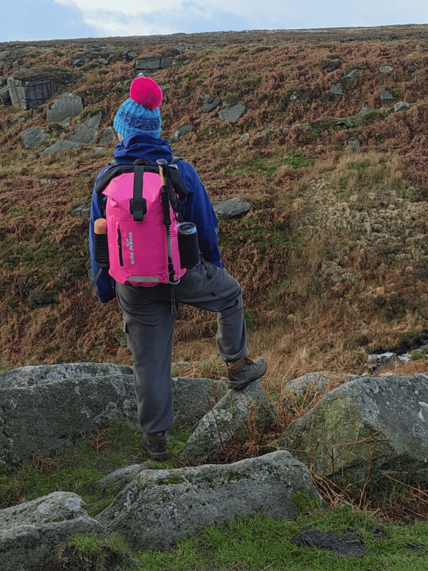Person hiking on a rocky hillside with a pink backpack