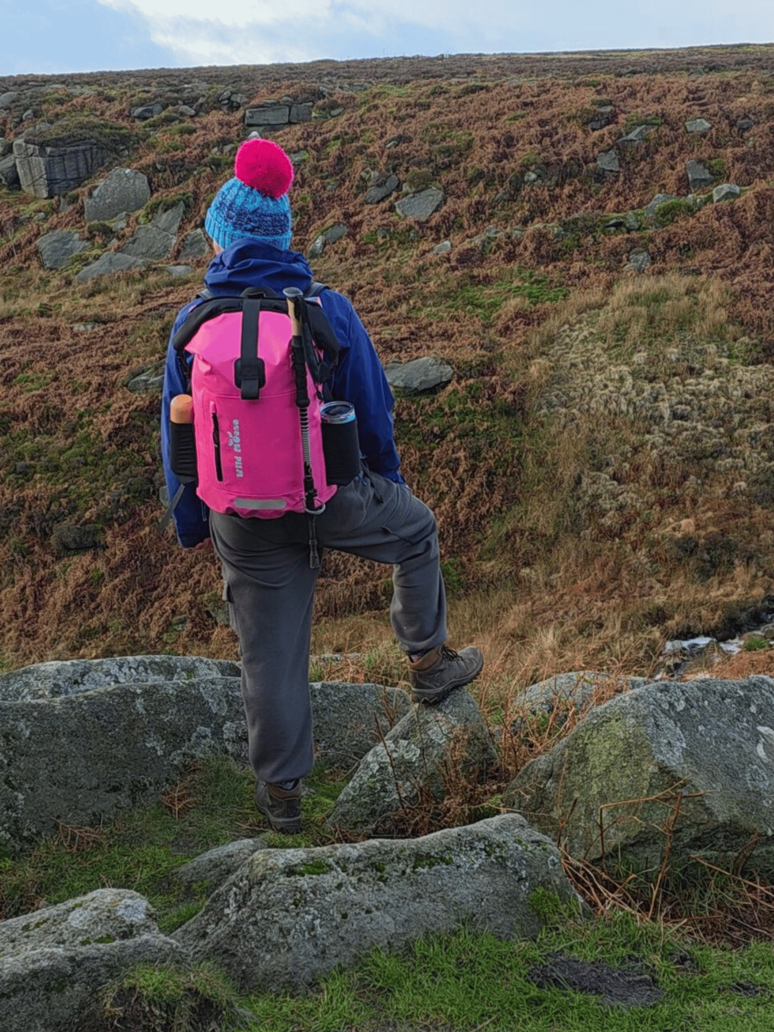 Person hiking on a rocky hillside with a pink backpack