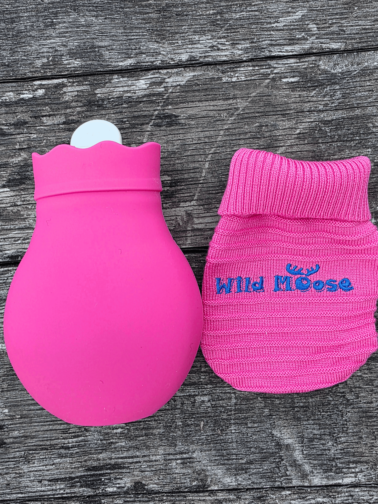 bright pink mini hot water bottle next to a matching pink knitted cover