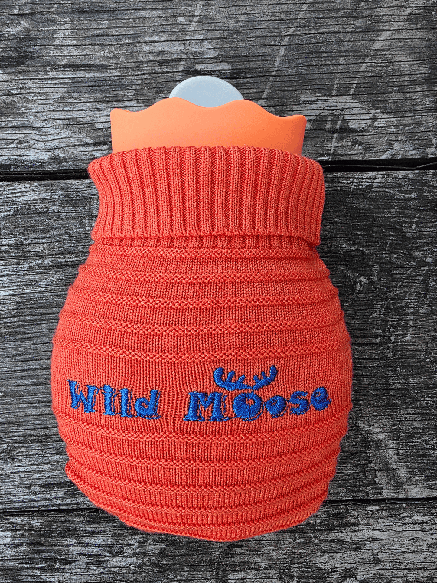 mini hot water bottle in a knitted cover in orange