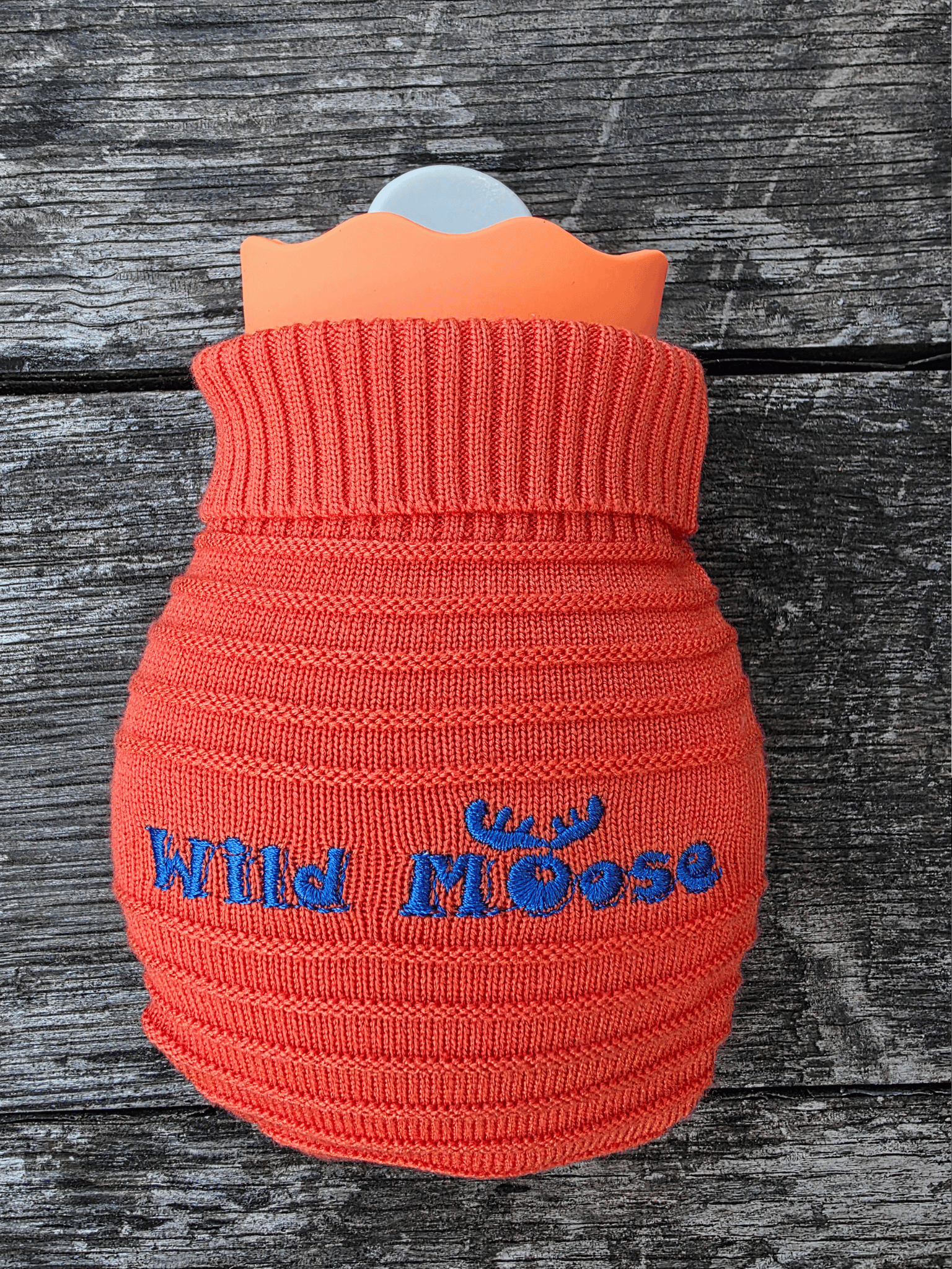 mini hot water bottle in a knitted cover in orange