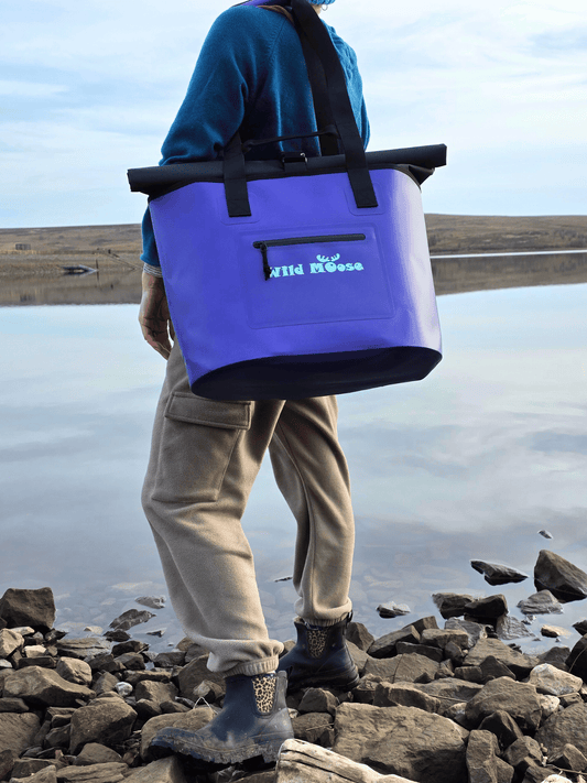lady with purple tote bag over shoulder looking at a rocky lake