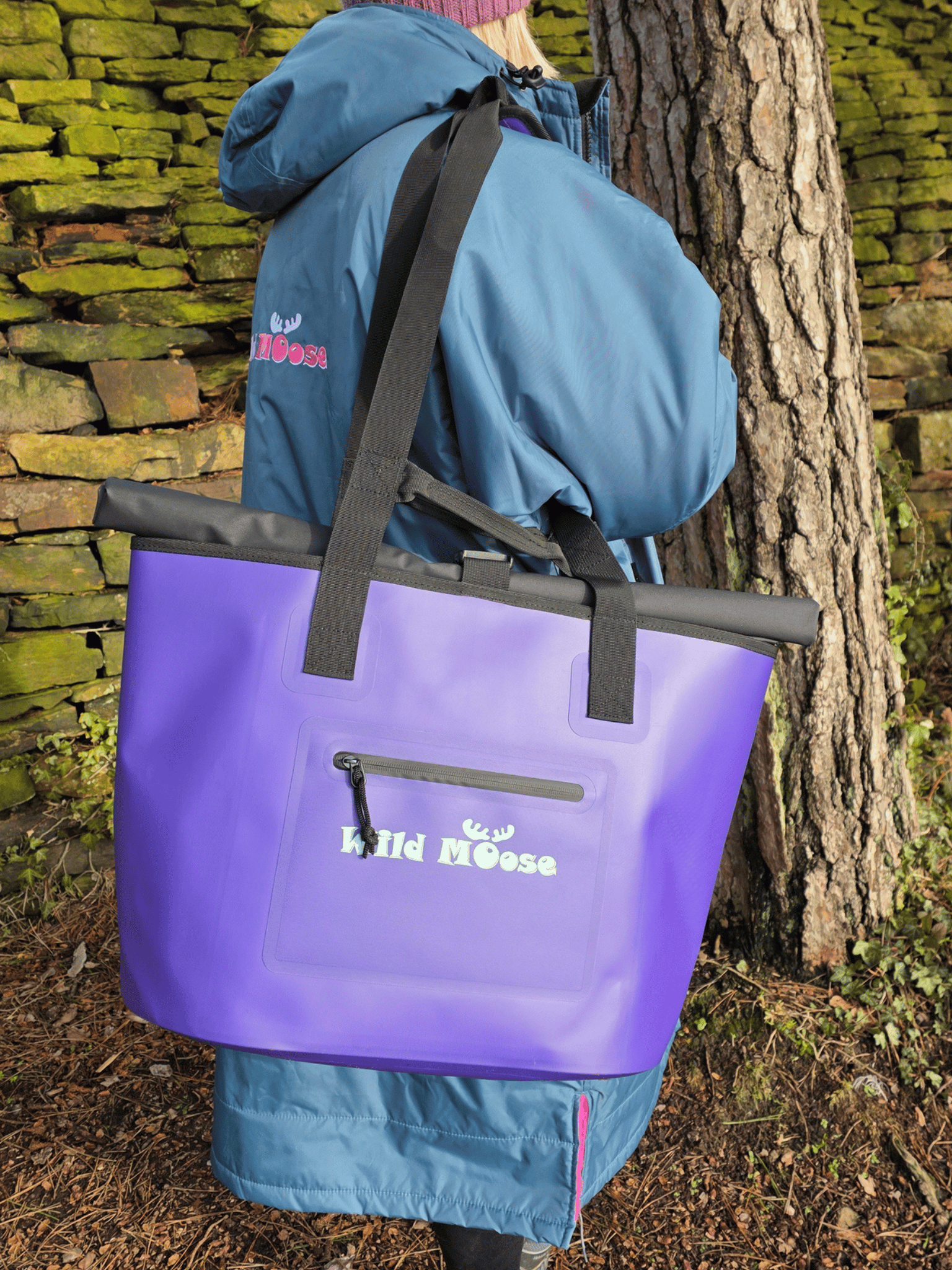 lady in blue robe with purple tote bag over shoulder stood next to a wall