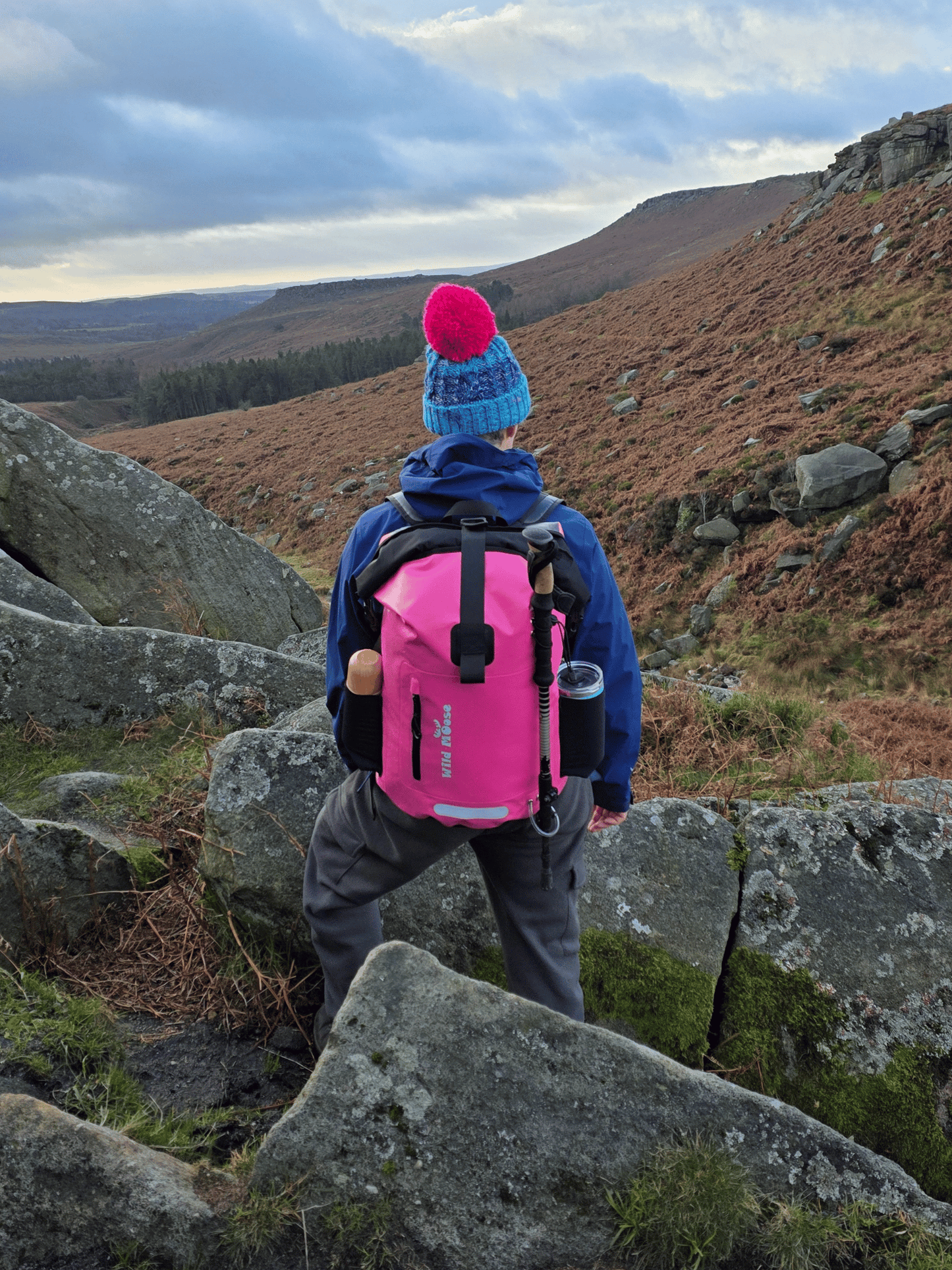 Person hiking in a mountainous area with a pink backpack